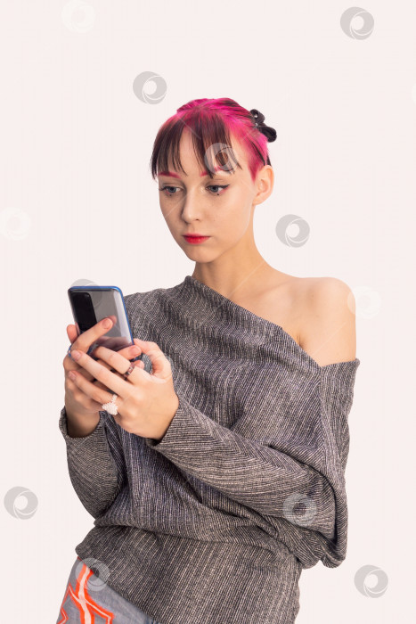 Скачать девушка-подросток смотрит в смартфон на светлом фоне фотосток Ozero
