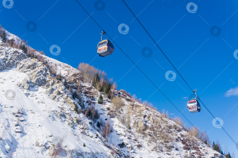 Скачать канатные дороги для лыжников на фоне голубого неба и заснеженных горных склонов, вид снизу вверх фотосток Ozero