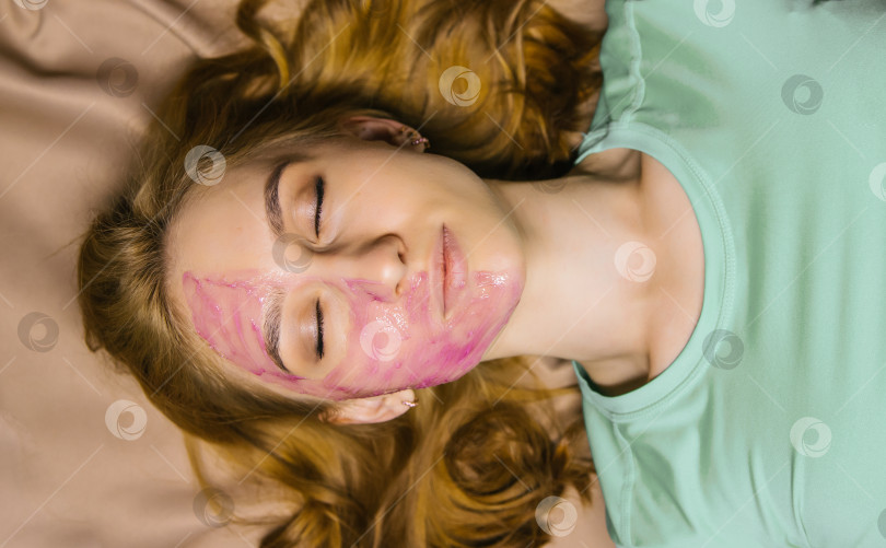 Скачать молодая женщина с розовой косметической маской на лице. Уход за кожей лица. фотосток Ozero