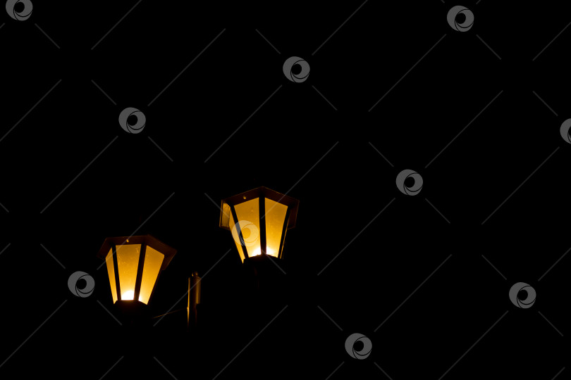 Скачать Желтые уличные фонари светятся в темноте на черном фоне фотосток Ozero