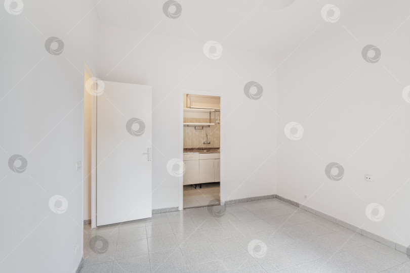 Скачать Пустая белая комната, соединенная с маленькой кухней. Типичная квартира в аренду в Барселоне. фотосток Ozero
