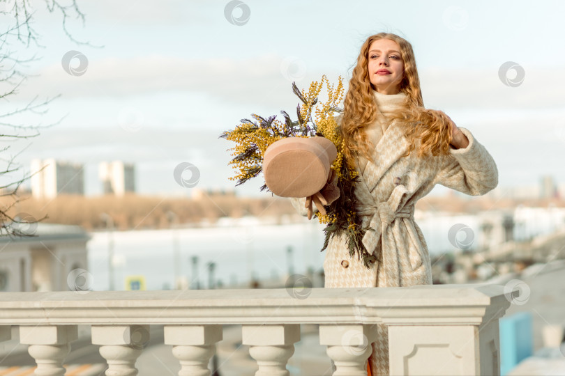 Скачать Молодая женщина стоит с букетом желтой мимозы и нюхает цветы. Концепция весеннего праздника - 8 марта, Пасха, Женский день. фотосток Ozero