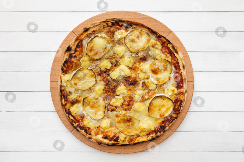 Скачать Пицца с козьим сыром на деревянной тарелке. Вид сверху на фоне белой доски фотосток Ozero