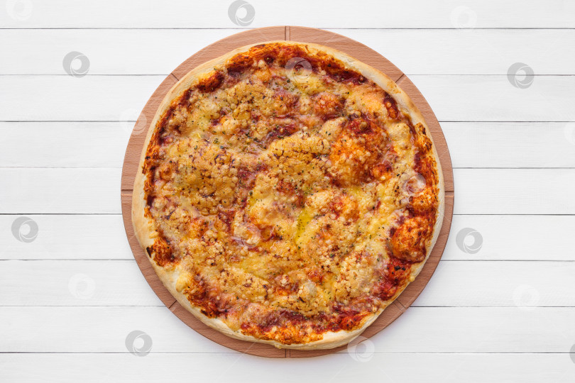 Скачать Цельнокруглая пицца, посыпанная сыром и орегано, на деревянной тарелке. Вид сверху на фоне белой доски фотосток Ozero