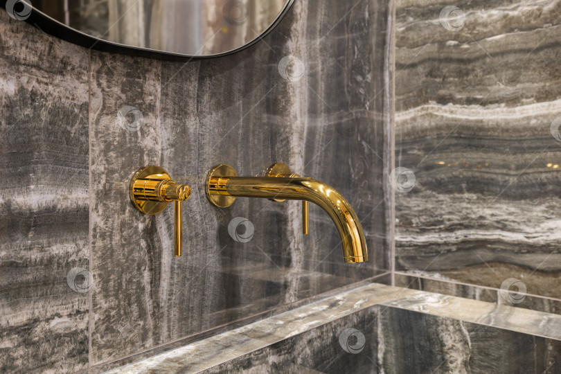 Скачать Крупный план современного золотого крана в умывальнике ванной комнаты с мраморной плиткой на стенах фотосток Ozero