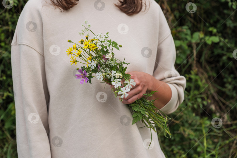 Скачать Деревенская девушка в белой блузке держит в руке полевые цветы. фотосток Ozero