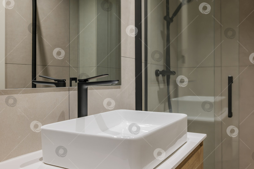 Скачать Крупный план белой раковины с черным краном и зеркалом. Интерьер ванной комнаты в современном стиле в отремонтированной квартире. фотосток Ozero