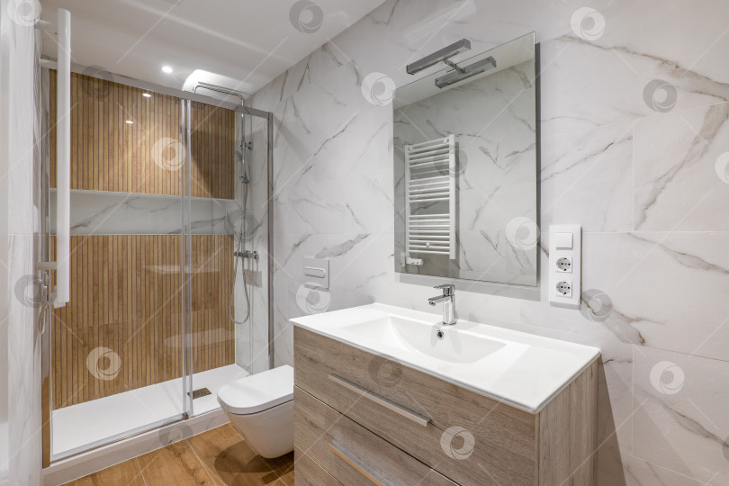 Скачать Интерьер современной отремонтированной ванной комнаты с душевой кабиной и деревянной отделкой фотосток Ozero