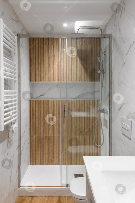Скачать Душевая зона с деревянной отделкой и стеклянной дверью. Интерьер современной отремонтированной ванной комнаты фотосток Ozero