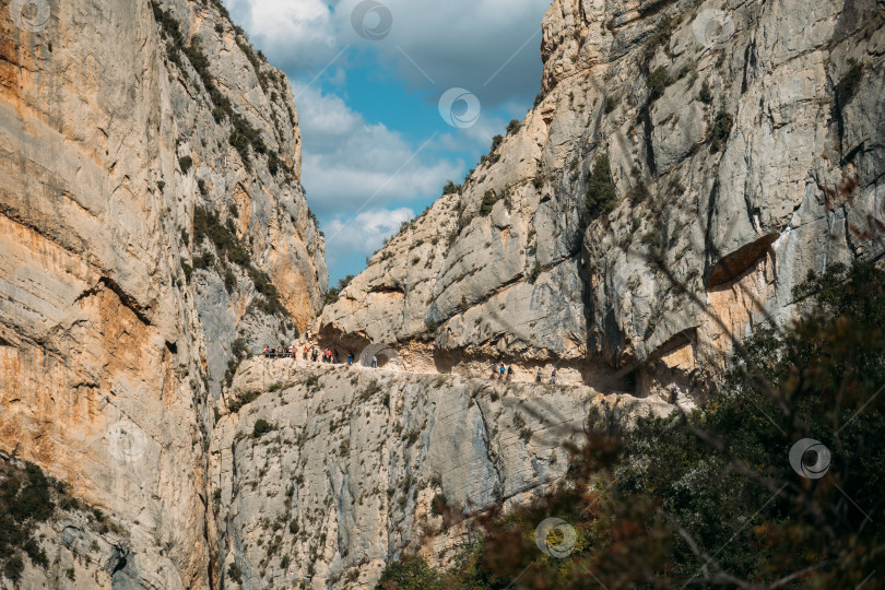 Скачать Впечатляющий утес с дорожкой внутри скалы, по которой люди совершают пешие походы. Конгост-де-Мон-Ребей, Каталония, Испания. фотосток Ozero