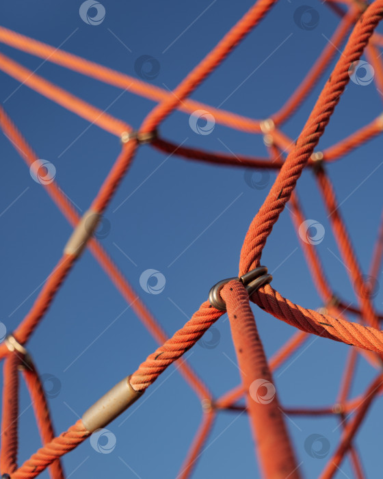Скачать Альпинистская веревочная сетка на фоне голубого неба. Крупный план части спортивно-игрового комплекса. фотосток Ozero