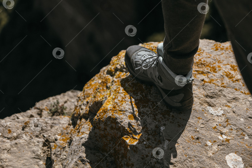 Скачать Деталь треккингового ботинка во время похода в горы, наступающего на край обрыва. фотосток Ozero