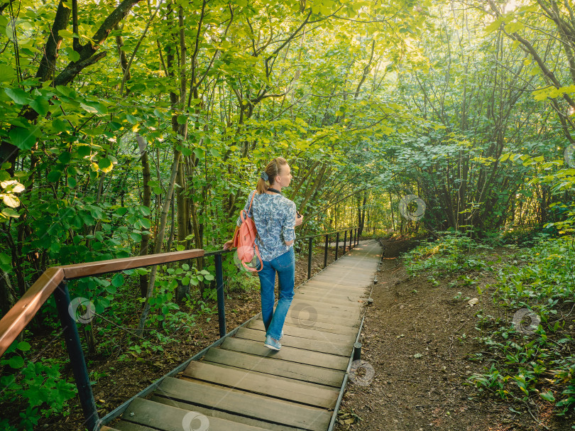 Скачать Активная стройная женщина с рюкзаком на крутой лестнице в зеленом лесу фотосток Ozero