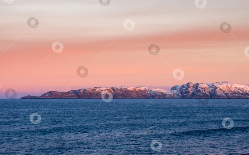 Скачать Прекрасный розовый закат над Северным Ледовитым океаном. Полуостров с заснеженными холмами на горизонте. Морской минималистичный пейзаж. фотосток Ozero
