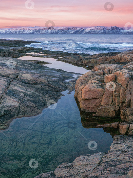 Скачать Удивительный пейзаж восхода солнца с полярно-белой заснеженной грядой гор. Чудесный горный пейзаж с ущельем и мысом на берегу Баренцева моря фотосток Ozero