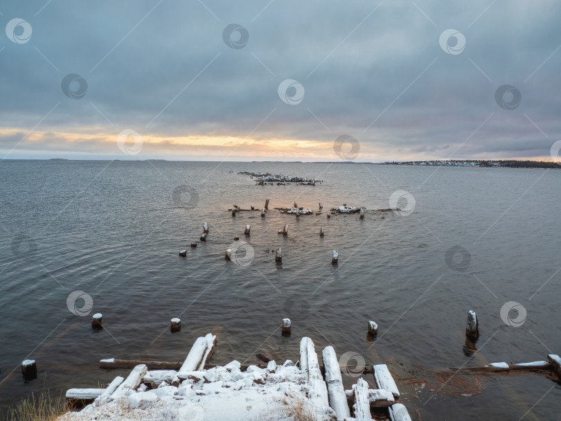 Скачать Зимний минималистичный пейзаж со старым разрушенным пирсом в Белом море. фотосток Ozero
