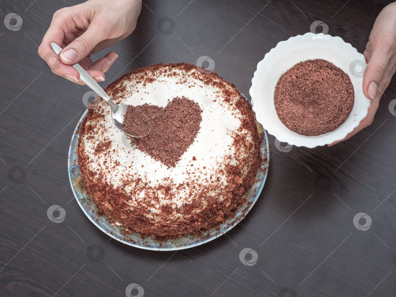 Скачать Украшаем торт ко дню святого Валентина. Пирог ручной работы с глазурью из сливочного сыра и шоколадным сердечком. Сладости на день святого Валентина фотосток Ozero