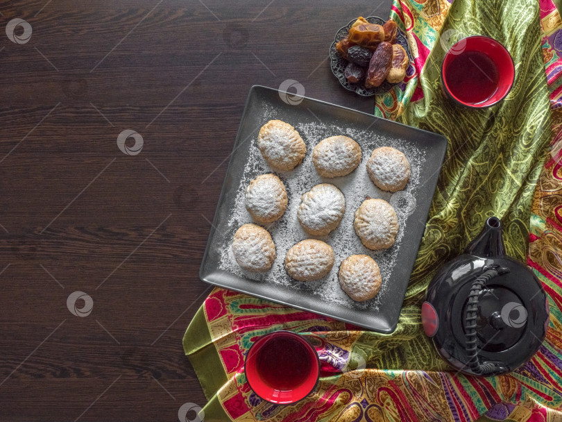 Скачать Сладости ручной работы в Рамадан подаются к чаю на столе из темного дерева. Египетское печенье "Кахк Эль-Ид" - печенье исламского праздника Эль-Фитр. Вид сверху. фотосток Ozero