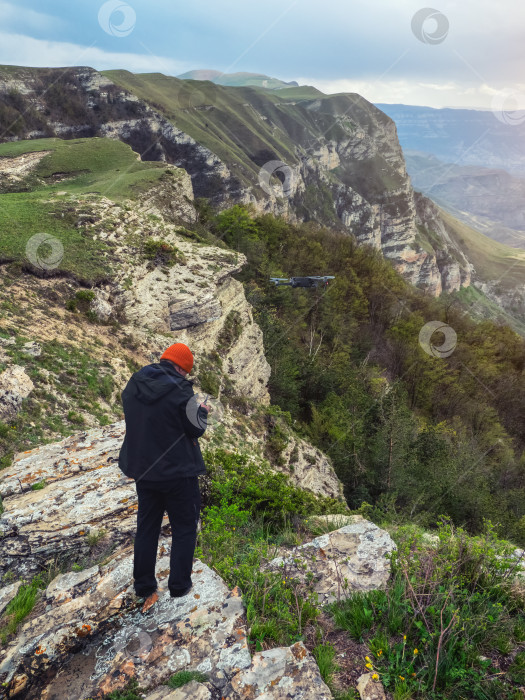 Скачать Фотограф с беспилотника запускает дрон на рассвете на утесе в горах. фотосток Ozero