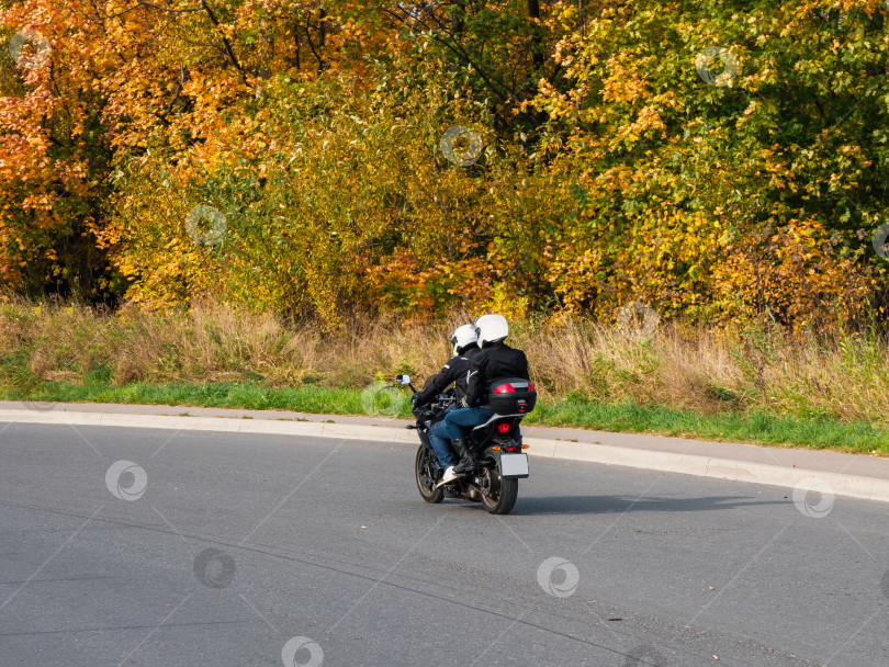 Скачать Пара байкеров на одном мотоцикле едет по осеннему шоссе фотосток Ozero
