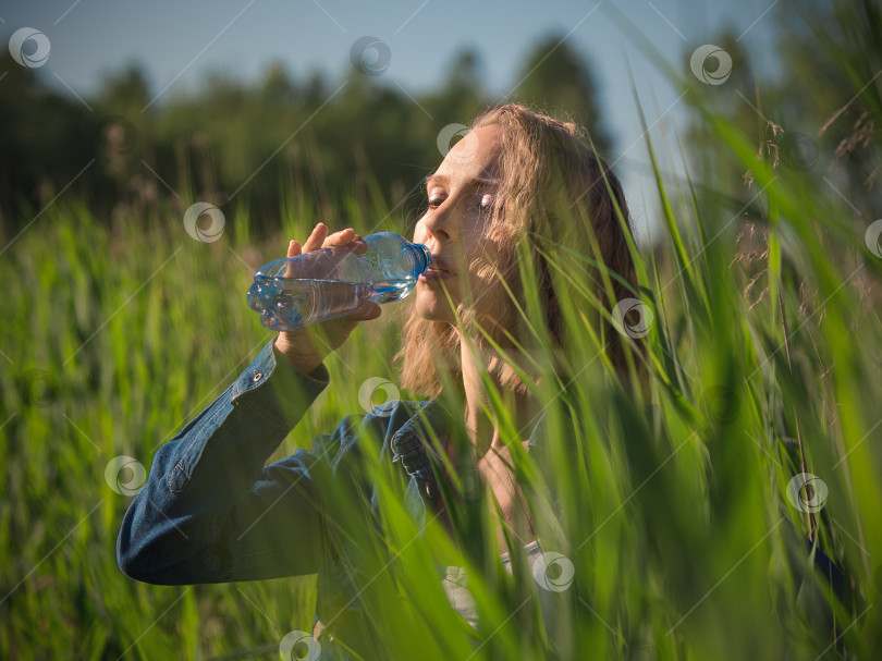 Скачать Женщина пьет воду из бутылки в жаркий летний день. Одиночное путешествие фотосток Ozero