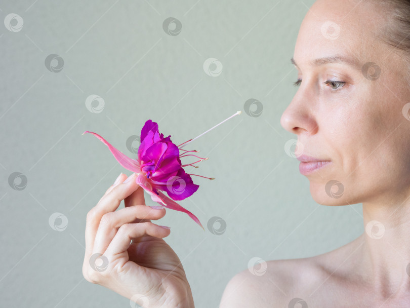 Скачать Привлекательная женщина лет сорока с цветком в руке фотосток Ozero
