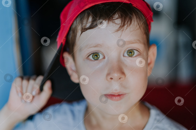 Скачать портрет крупным планом большеглазого мальчика в кепке с зелеными глазами, похожего на бездомного ребенка и хулигана фотосток Ozero