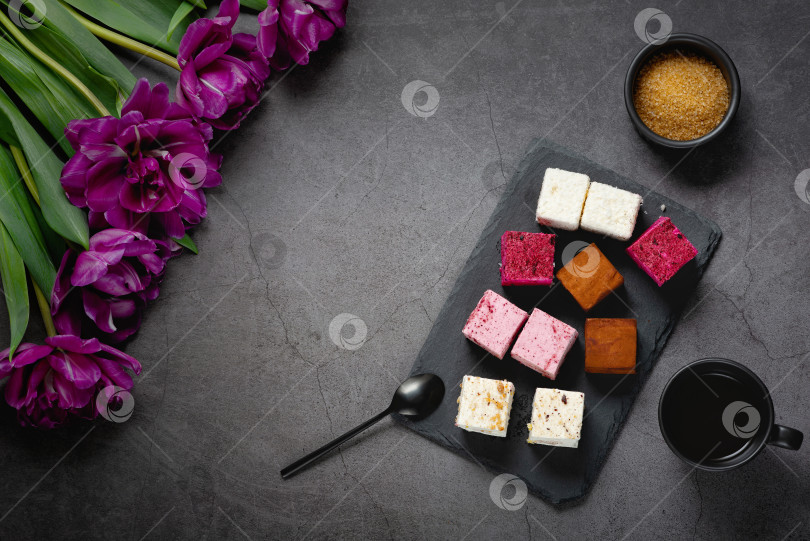 Скачать Пирожные и кофе на темном столе, украшенном букетом красивых тюльпанов. фотосток Ozero
