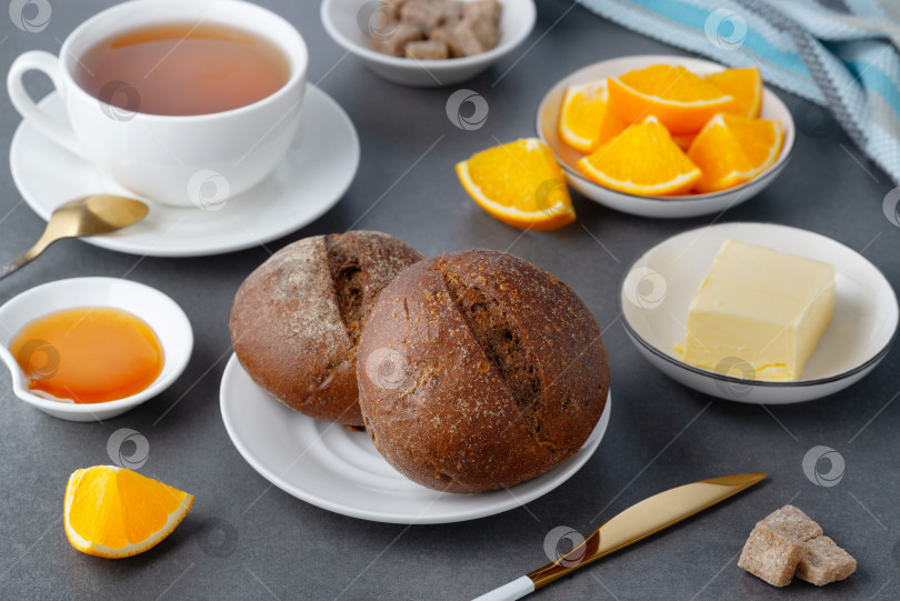 Скачать Ржаные булочки и сливочное масло для завтрака с чаем и апельсином фотосток Ozero