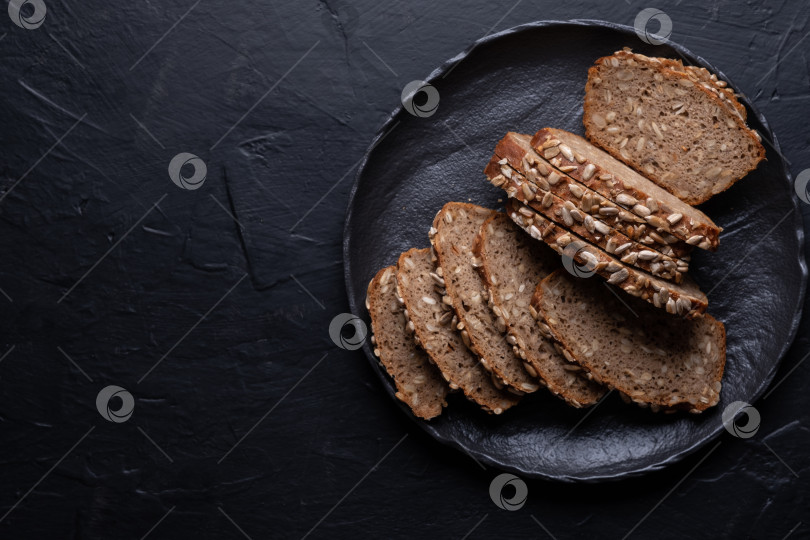 Скачать Нарезанный ржаной хлеб на черном столе. Цельнозерновой ржаной хлеб с семенами фотосток Ozero