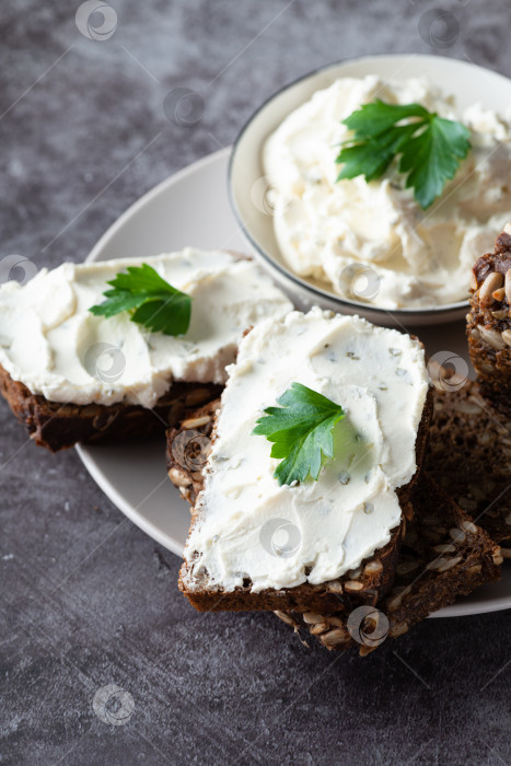 Скачать Ржаной хлеб со сливочным сыром на сером столе. Цельнозерновой ржаной хлеб с семенами фотосток Ozero