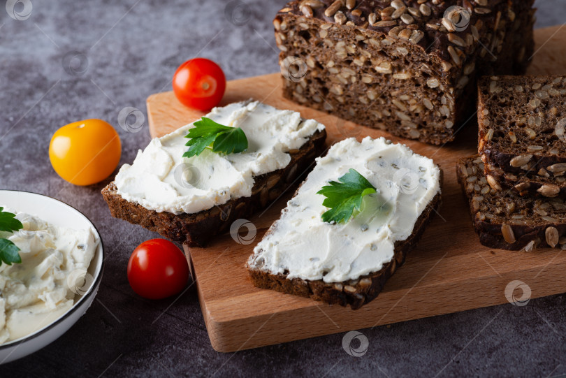 Скачать Ржаной хлеб со сливочным сыром на сером столе. Цельнозерновой ржаной хлеб с семенами фотосток Ozero