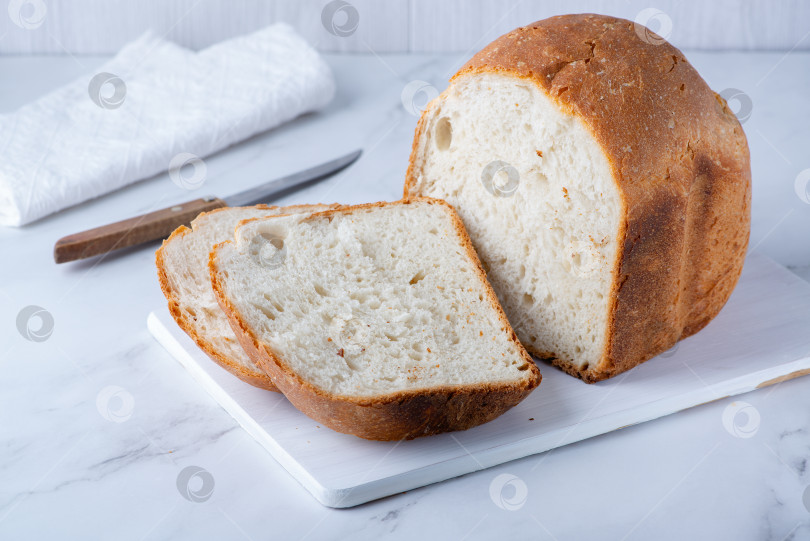 Скачать Свежий хлеб на деревянной подушке. Свежеиспеченный хлеб на белом столе. Здоровая пища фотосток Ozero