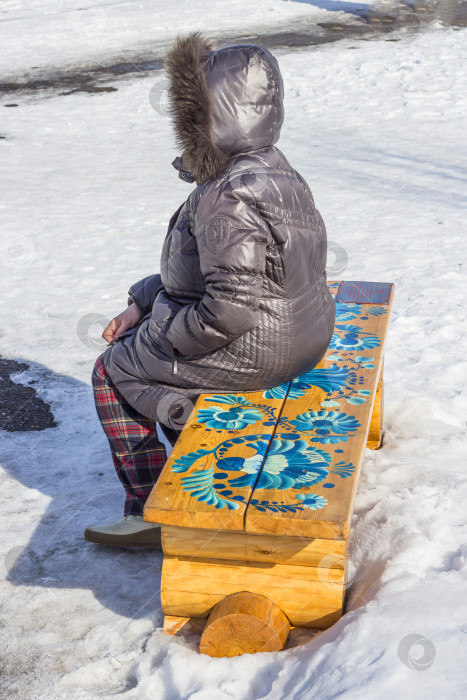 Скачать Женщина сидит на скамейке, украшенной орнаментом в стиле русской Гжели фотосток Ozero