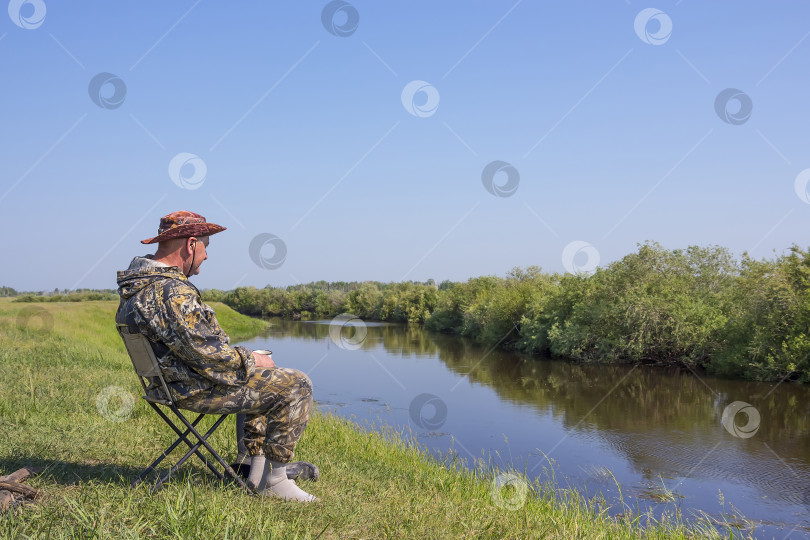 Скачать Рыбак пьет чай и любуется красотой реки в летний день фотосток Ozero