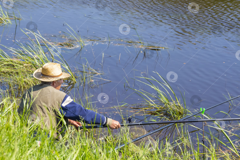 Скачать Рыбак летним днем ловит рыбу на реке на поплавке фотосток Ozero
