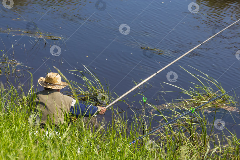 Скачать Рыбак летним днем ловит рыбу на реке на поплавке фотосток Ozero