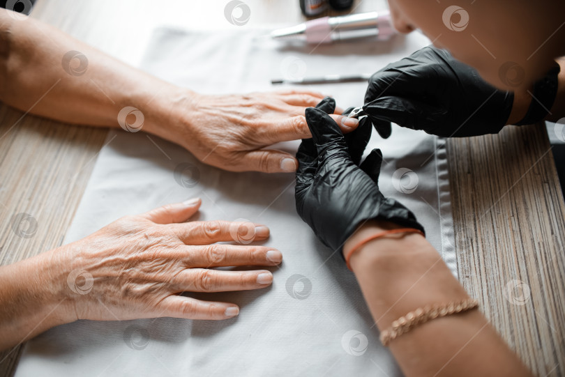 Скачать Мастер маникюра ухаживает за ногтями пожилой женщины крупным планом фотосток Ozero