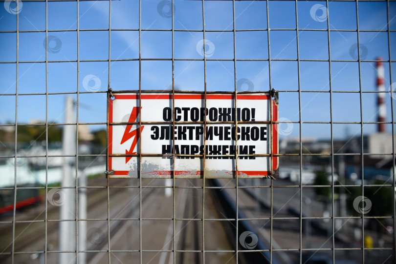 Скачать Специальный знак на заборе с надписью Осторожно Предупреждение об опасности электрического напряжения фотосток Ozero