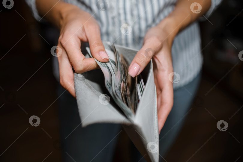 Скачать Женщина пересчитывает деньги, крупным планом бумажник с рублевыми купюрами. Выборочный фокус, темный фон фотосток Ozero