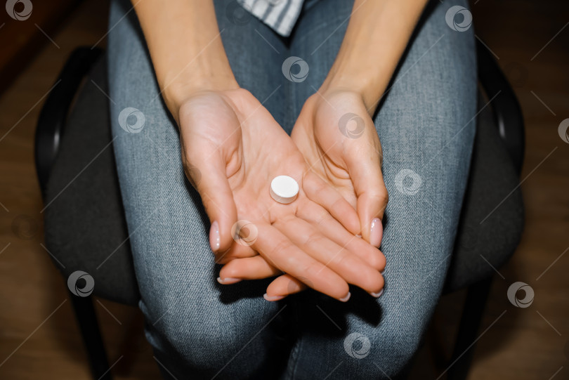 Скачать Женщина держит в руках таблетку. Молодая женщина собирается принимать лекарство. Укороченные фотосток Ozero