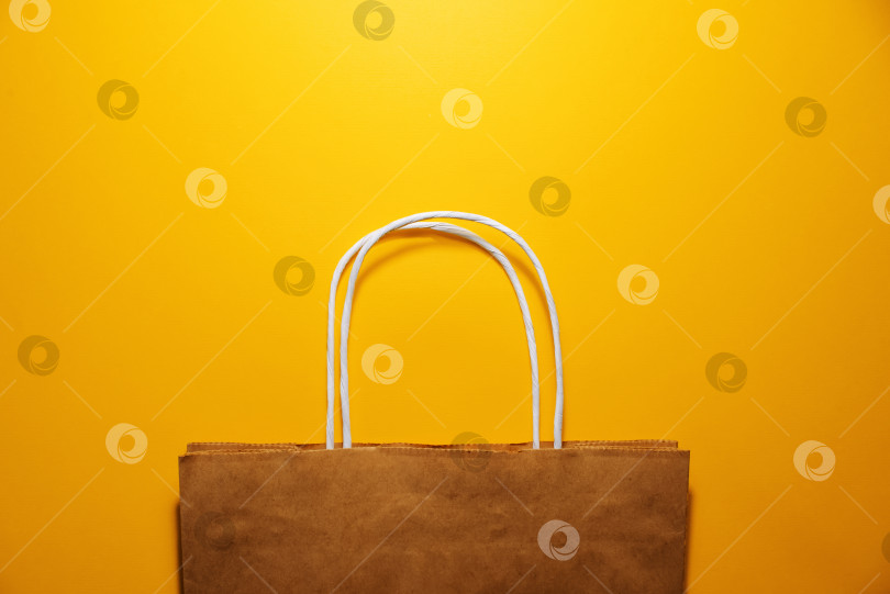 Скачать Хозяйственная сумка на ярко-желтом фоне, вид сверху. Концепция "черной пятницы", распродажа, скидки, шоппинг. Пространство для копирования фотосток Ozero