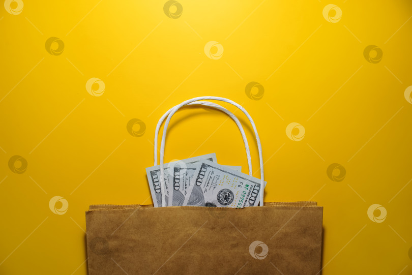 Скачать Деньги, сумка на желтом фоне, вид сверху. Доллары в хозяйственной сумке. Шоппинг, черная пятница, концепция распродажи. Пространство для копирования фотосток Ozero