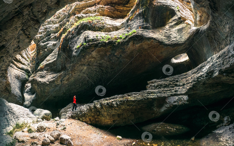 Скачать Женский силуэт в огромной пещере. Салтинское ущелье в горном ландшафте Дагестана. фотосток Ozero