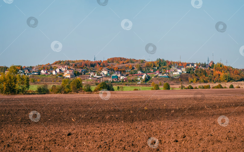 Скачать Пейзаж с сельскохозяйственными угодьями, подготовленными к посеву, с деревней на заднем плане фотосток Ozero