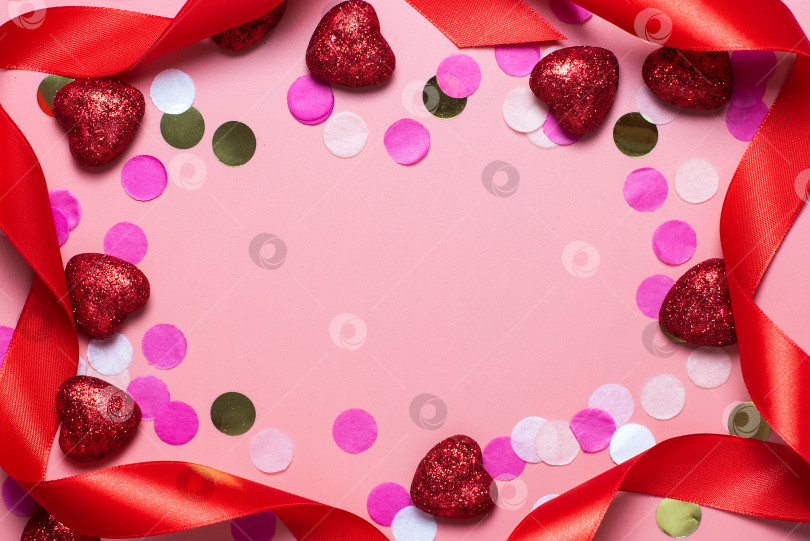 Скачать рамка. пустая открытка на день святого Валентина. на розовом фоне конфетти, лента и красные сердечки. забавные поздравления. Плоское положение, вид сверху. красные блестящие сердечки фотосток Ozero