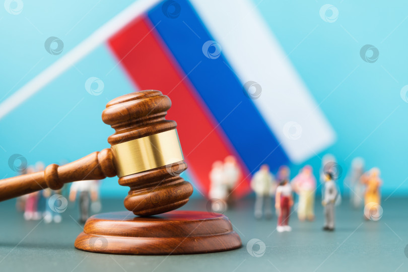 Скачать Судья молоток на фоне размытого флага и игрушечных пластиковых человечков, концепция судебного разбирательства в российском обществе фотосток Ozero