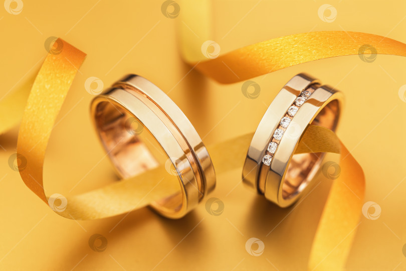 Скачать Два обручальных кольца, соединенных лентой на желтом фоне фотосток Ozero