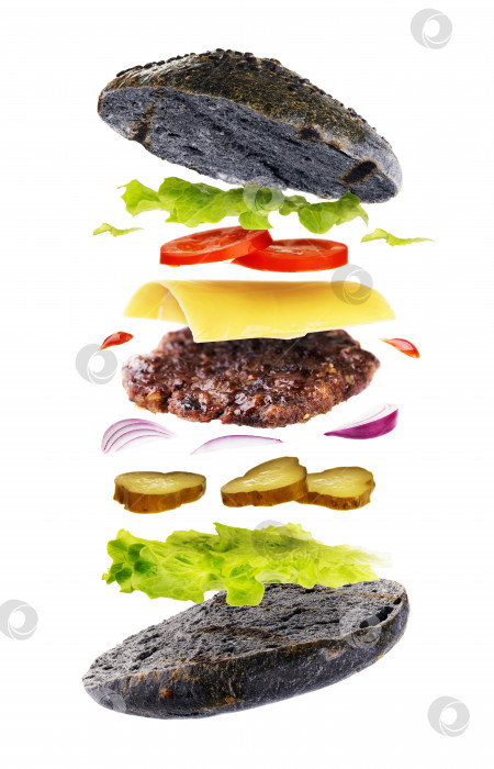 Скачать Вкусный гамбургер с хлебом черного цвета, выделенным на белом фоне. Свежеиспеченный бургер с летающими ингредиентами фотосток Ozero