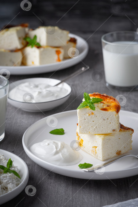 Скачать Творожная запеканка с изюмом и чашкой молока на сером фоне дерева. Творожная запеканка. фотосток Ozero